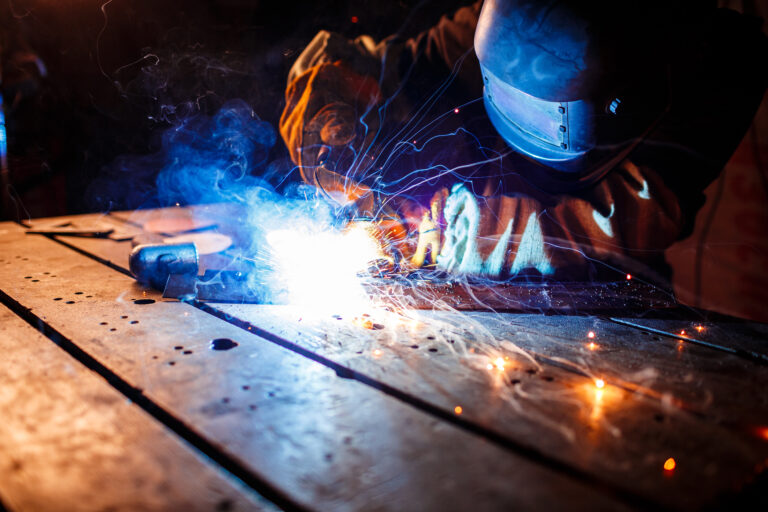 Worker cutting metal with plasma equipment on plant.